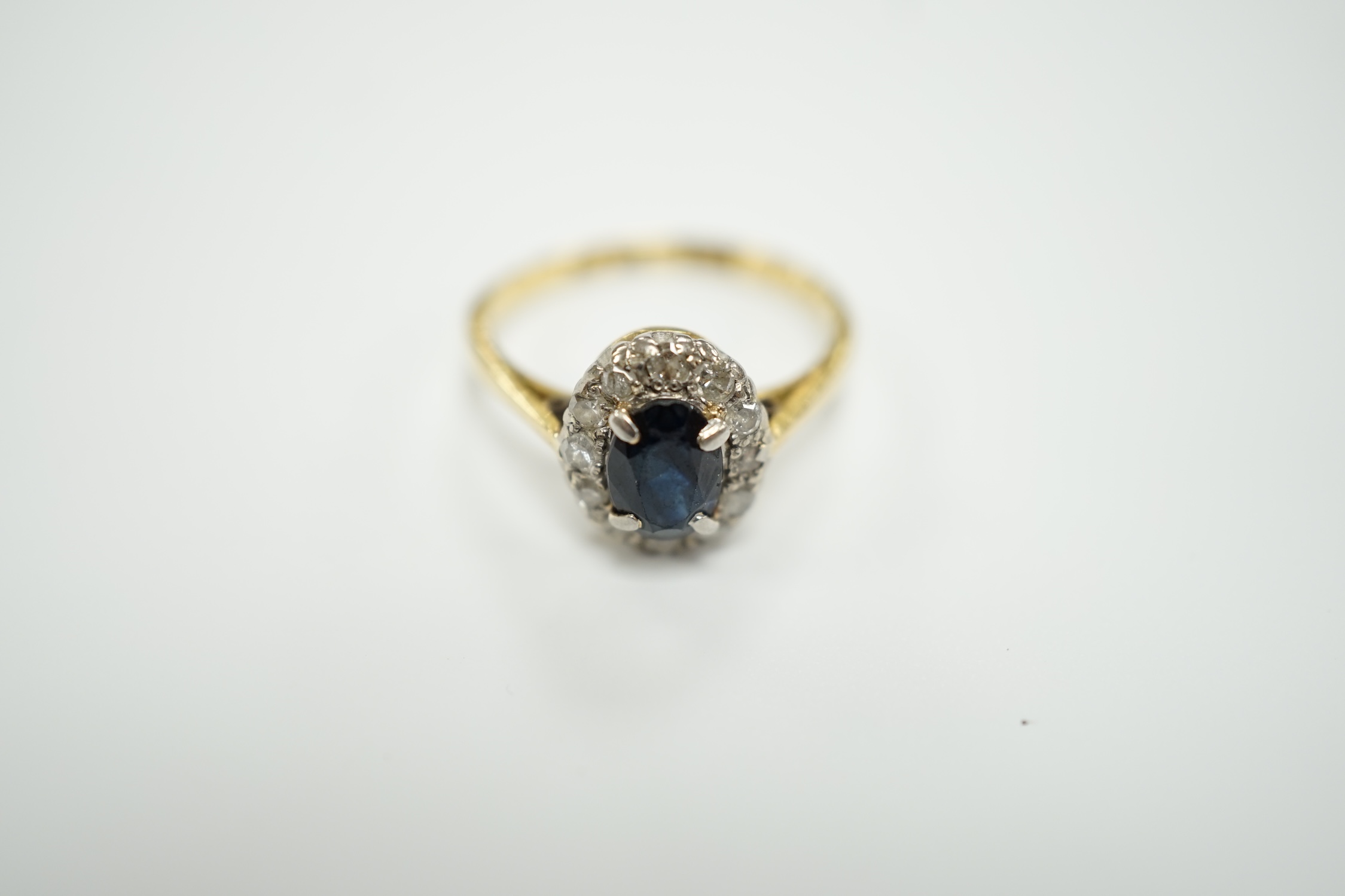 An 18ct, sapphire and diamond set oval cluster ring, size L, gross weight 2.5 grams.